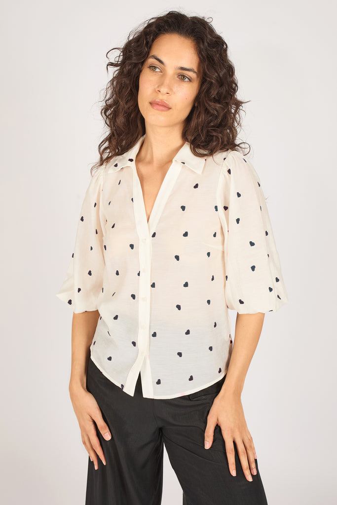 Another close up front model shot of a cream button up top with navy blue heart print and three quarter length sleeves