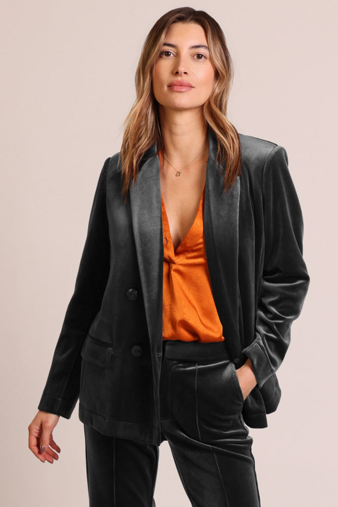 Close up front shot of model wearing black cord velvet long sleeve button front blazer jacket.
