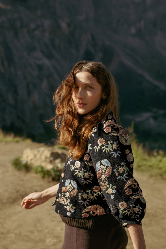 Shot of model wearing a black and multicolour floral embroidered jacket in a natural setting.