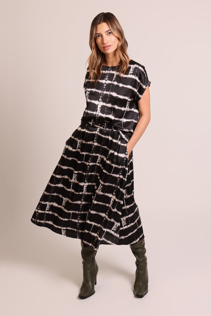 Front shot of model wearing a black and white brick wall print belted midi skirt with pockets.