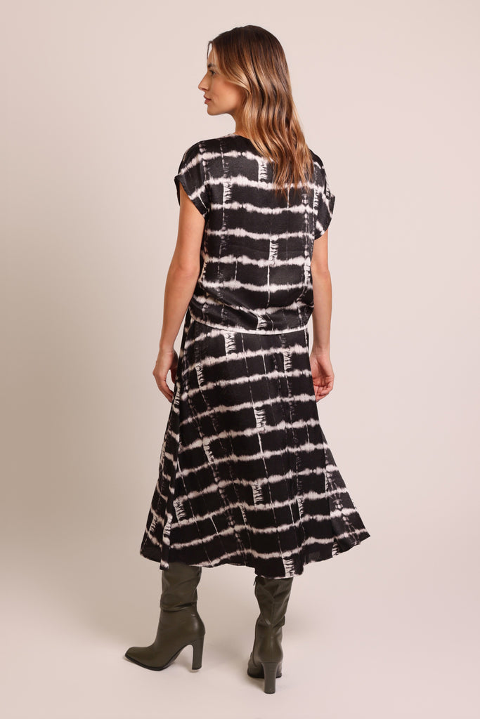 Back shot of model wearing a black and white brick wall print belted midi skirt with pockets.