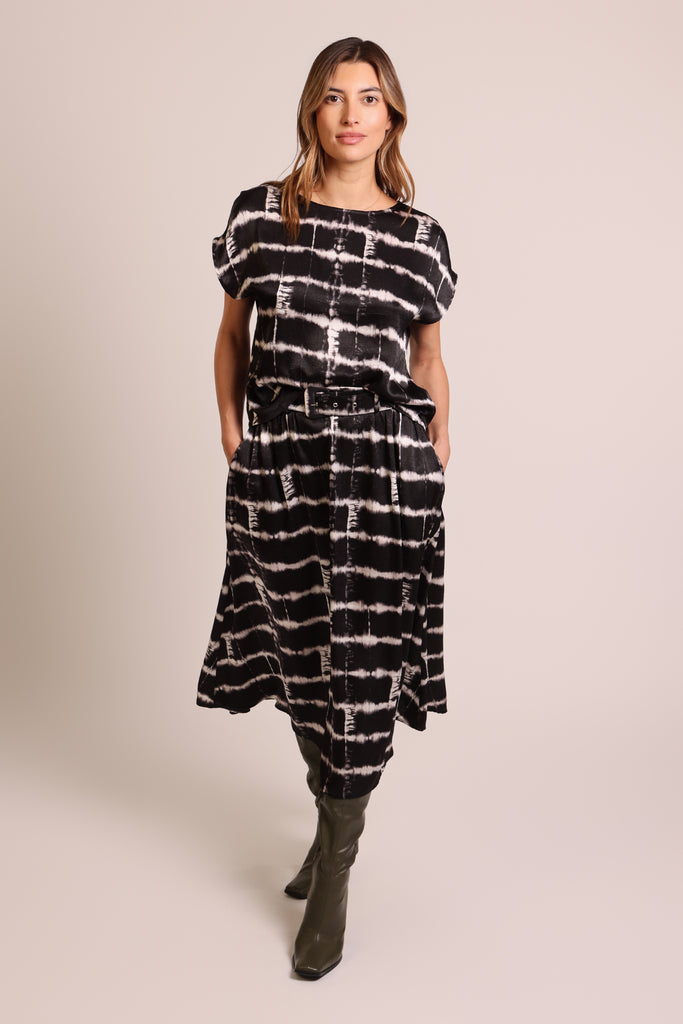 Front shot of model wearing a black and white brick wall print belted midi skirt with pockets.