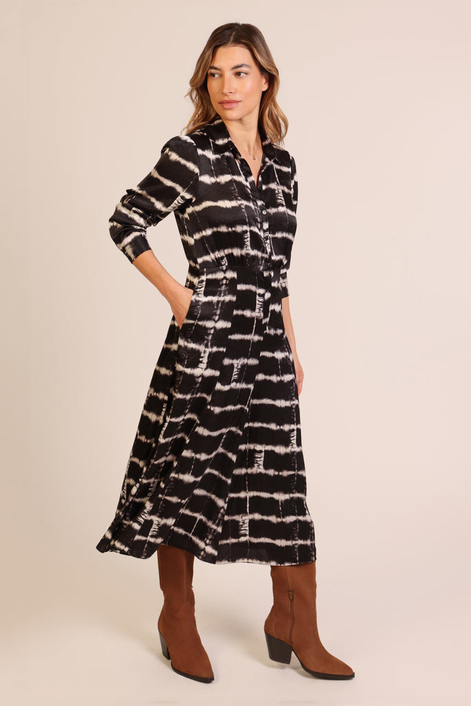 Side shot of model wearing a black and white brick wall print button front three quarter sleeve midi dress.