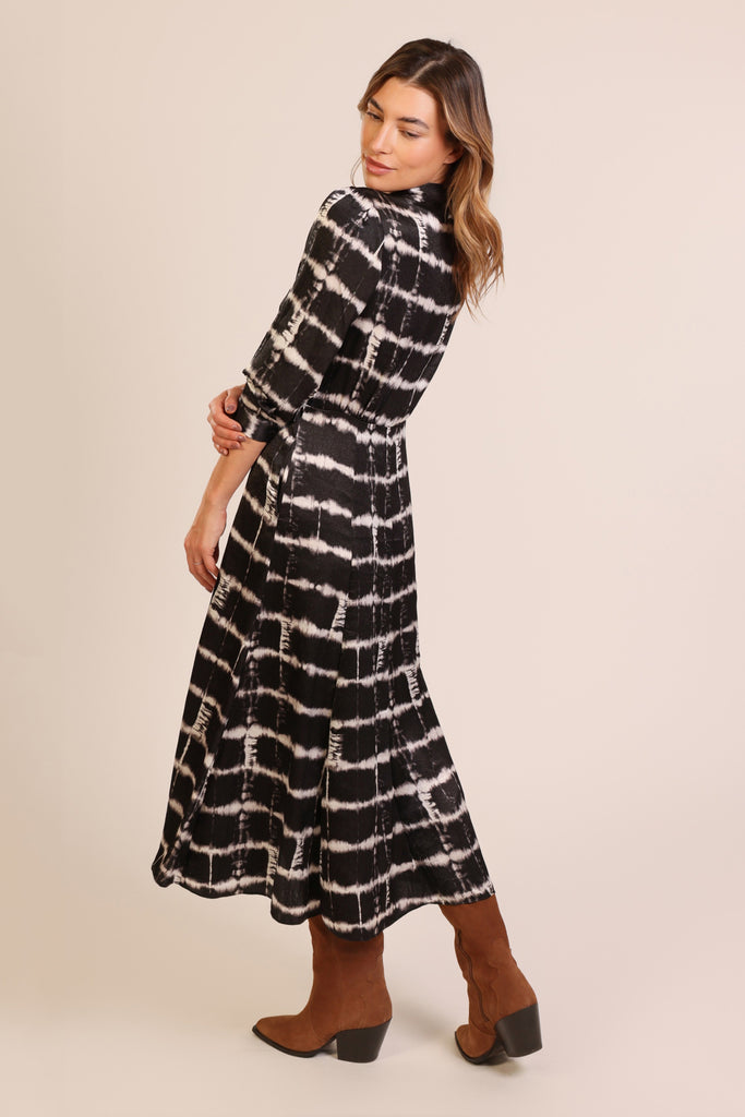 Back shot of model wearing a black and white brick wall print button front three quarter sleeve midi dress.