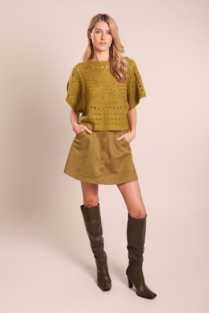 Front shot of model wearing a green knitted short sleeve relaxed fit jumper.