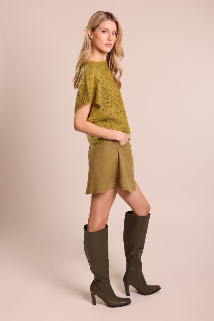 Side shot of model wearing a green knitted short sleeve relaxed fit jumper.
