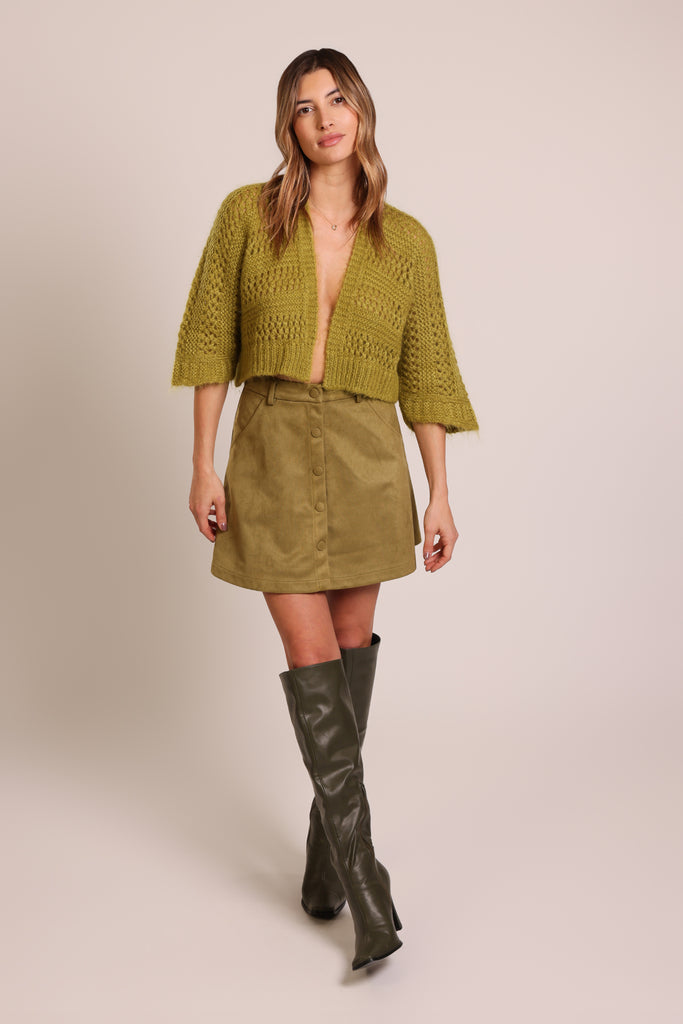 Front shot of model wearing a knitted green three quarter sleeve unfastened cardigan.