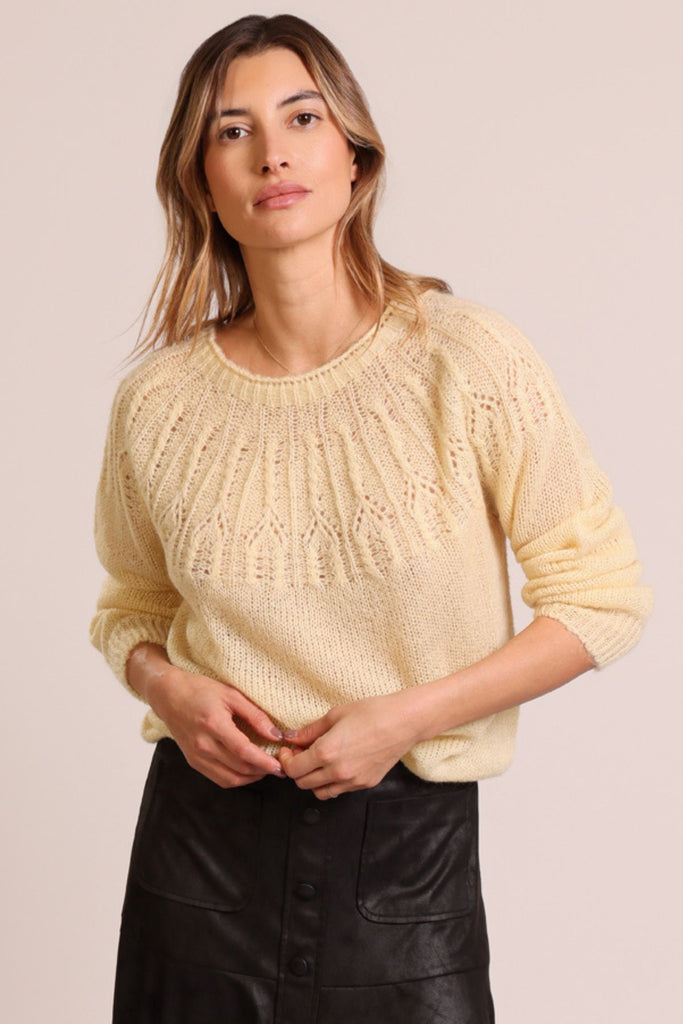 Close up front shot of model wearing a cream knitted long sleeve round neck jumper.